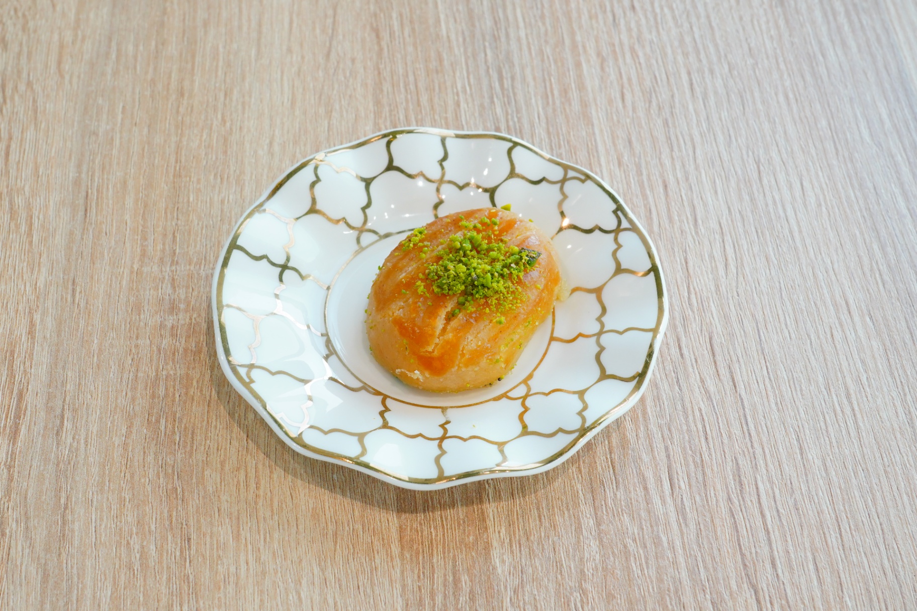 Pistachio-topped semolina pastry on a gold-trimmed plate