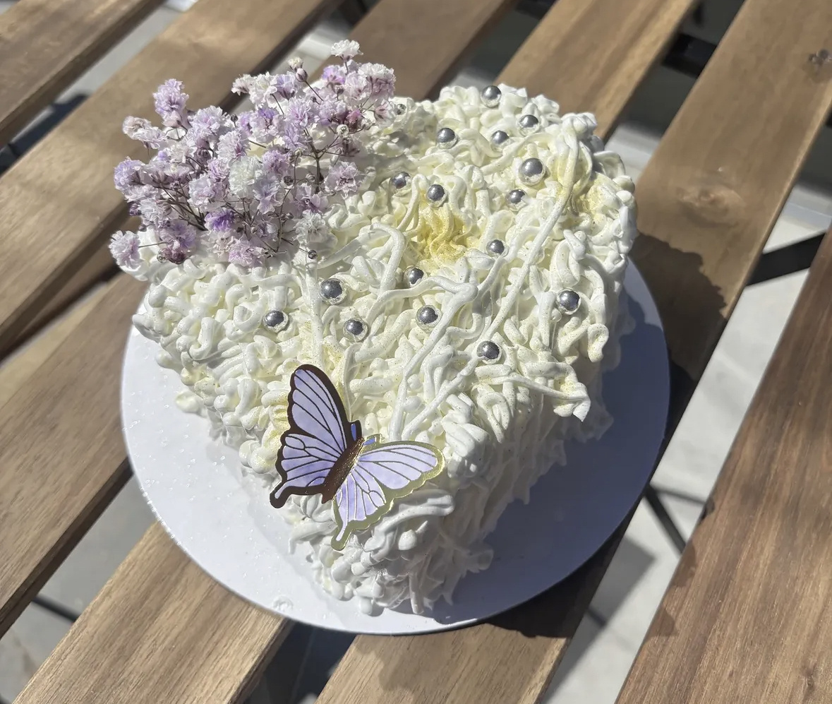 Heart-shaped cream cake with butterfly and dried florals